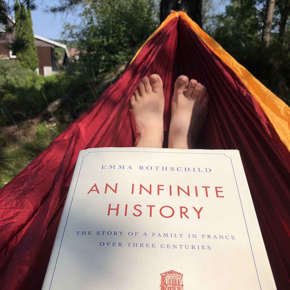 Bokomslag til An Infinite History av Emma Rothschild, i en hengekøye der to bare føtter skimtes i bakgrunnen