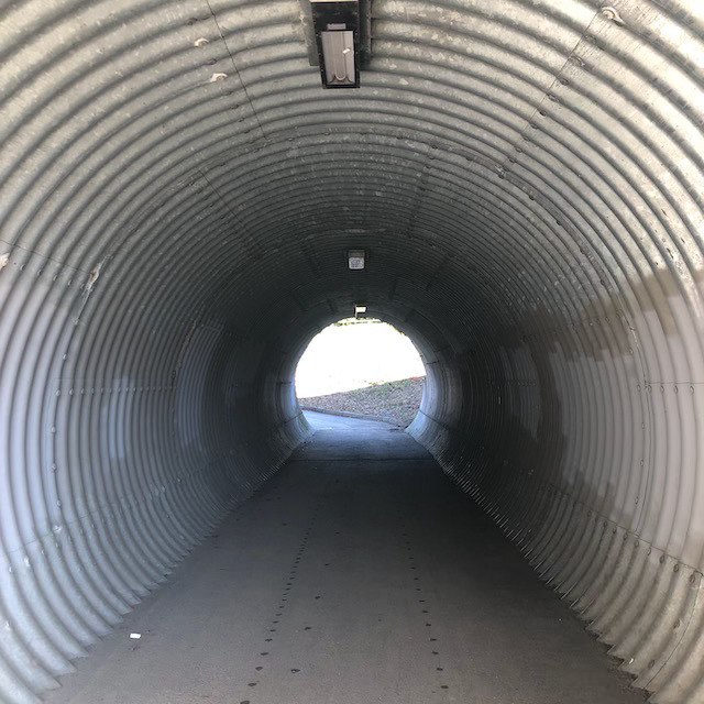 Grå tunnel for fotgjengere, lys i enden.