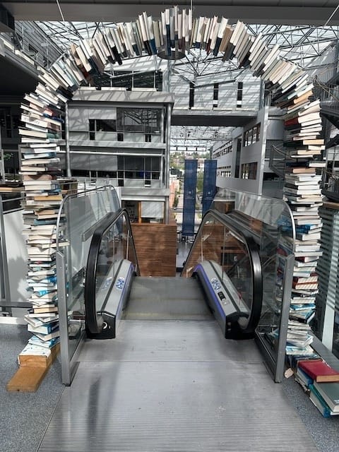 Portal laget av bøker foran en rulletrapp.